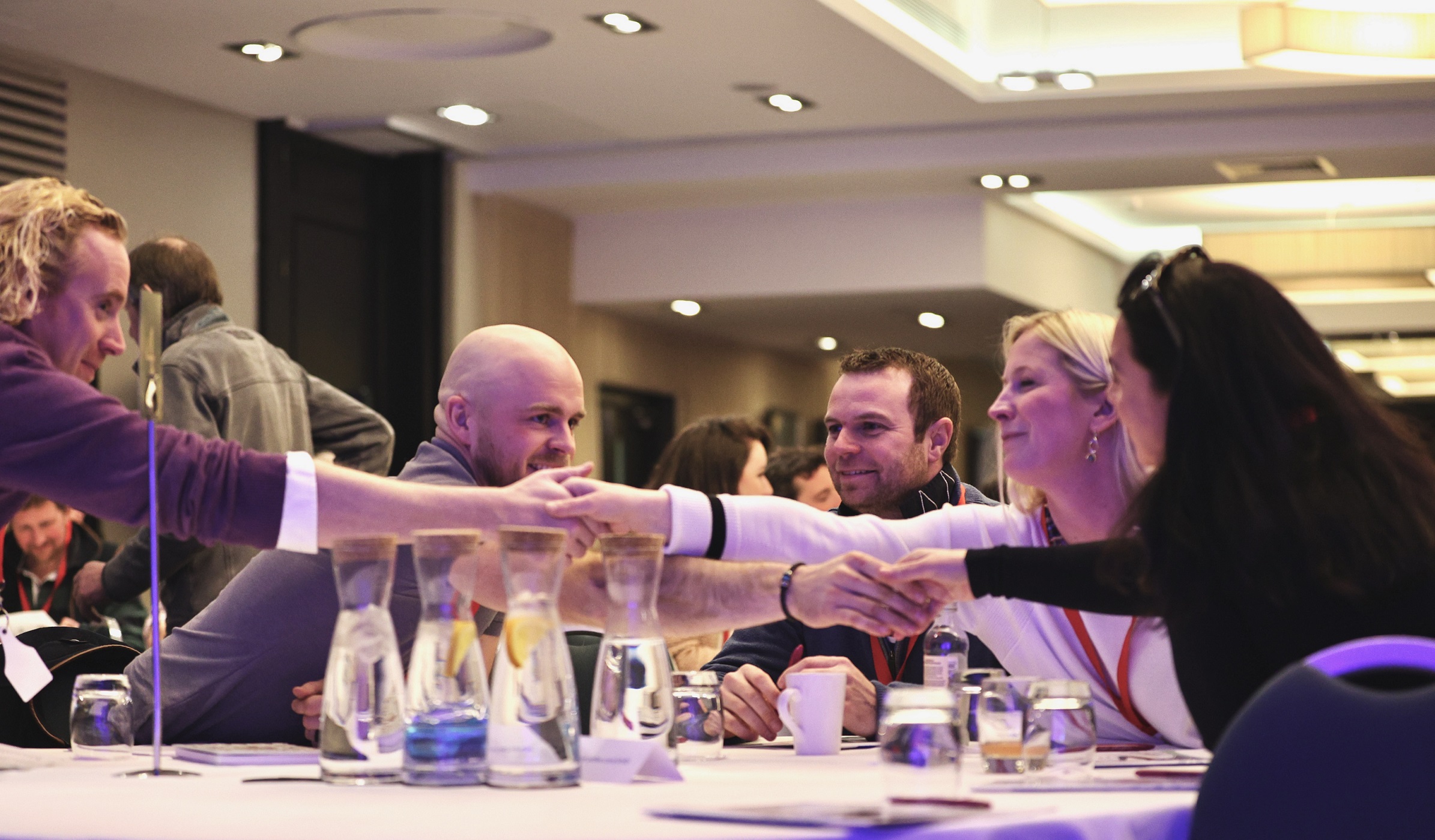 Delegates at a conference shaking hands across a table